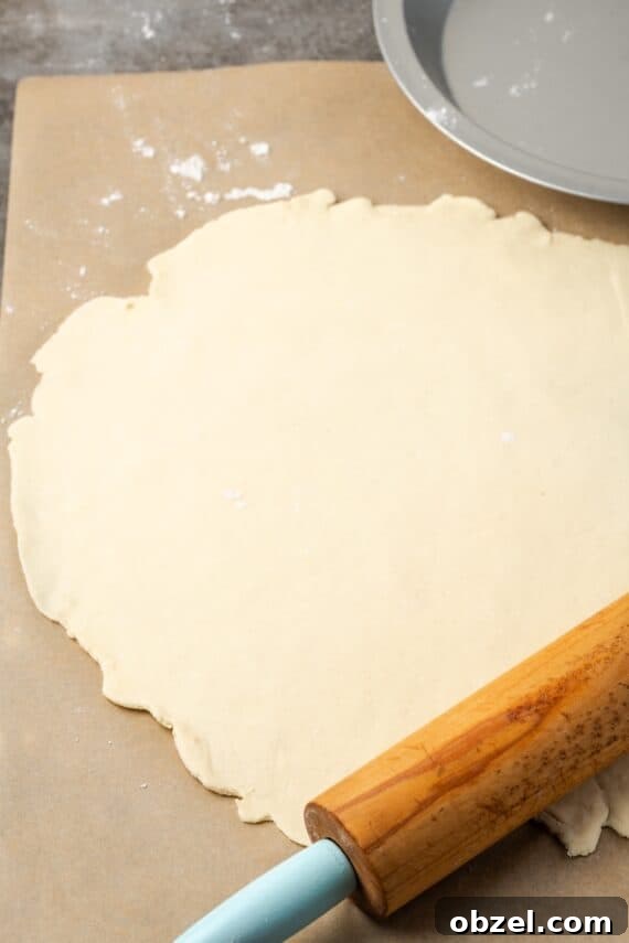 Rolled pie dough for cherry pie. Rolled out pie dough next to a rolling pin on a floured surface.