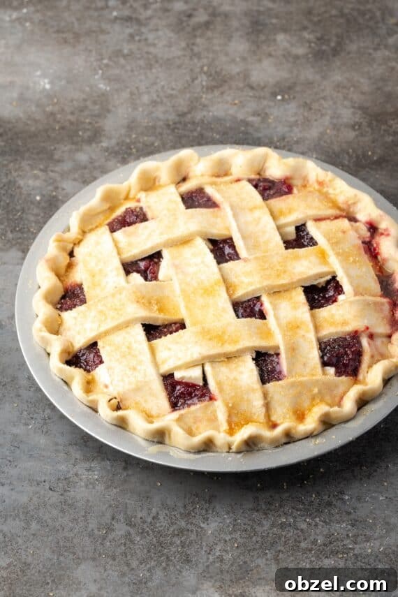 Cherry pie sprinkled with coarse sugar before baking. Cherry pie topped with an egg wash and coarse sugar, ready to bake.