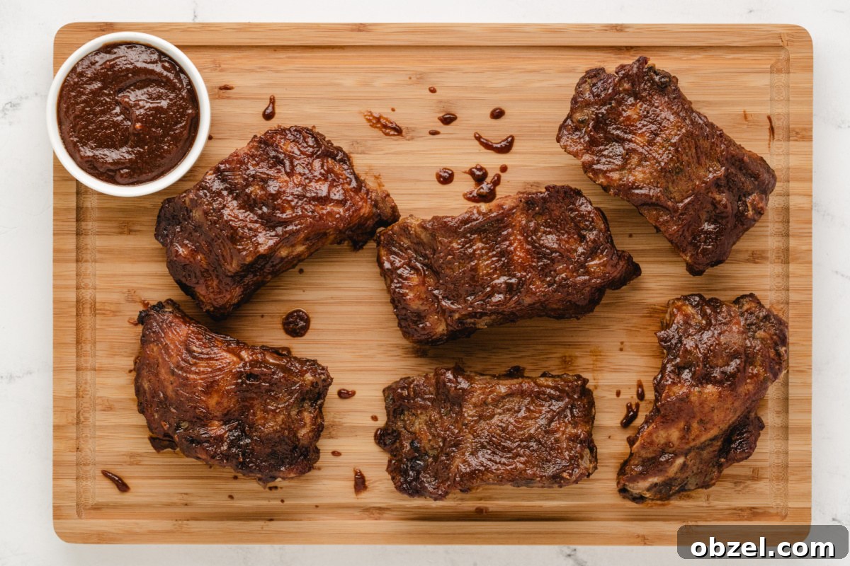 Juicy Slow Cooker Baby Back Ribs Recipe 7 baby back ribs on a board with a bowl of sauce