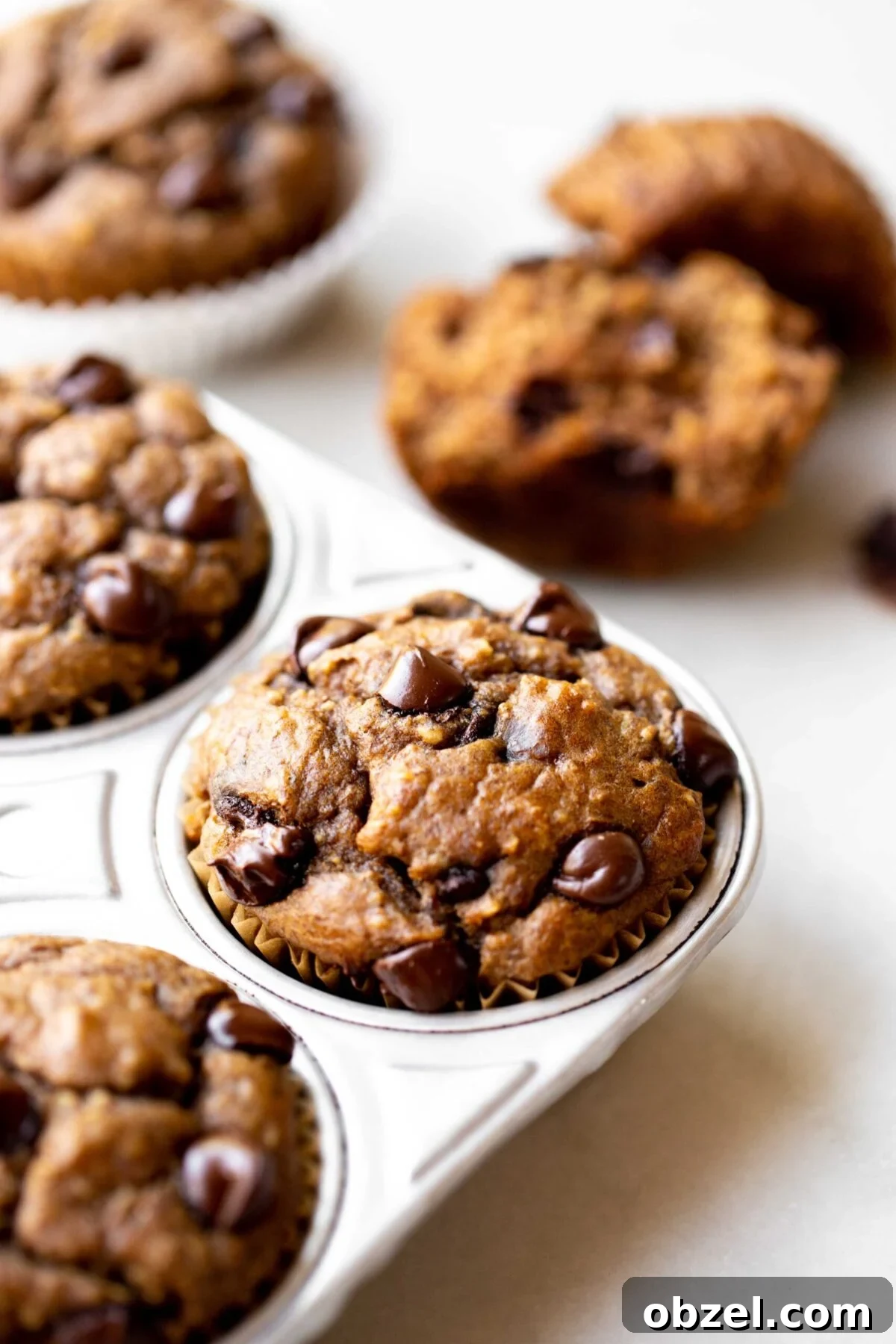 Banana Lentil Muffins: Protein-Packed Breakfast Treat 5 closeup photo at 45 degree angle of freshly baked healthy chocolate chip banana muffins in an aluminum muffin pan on a light gray marble background