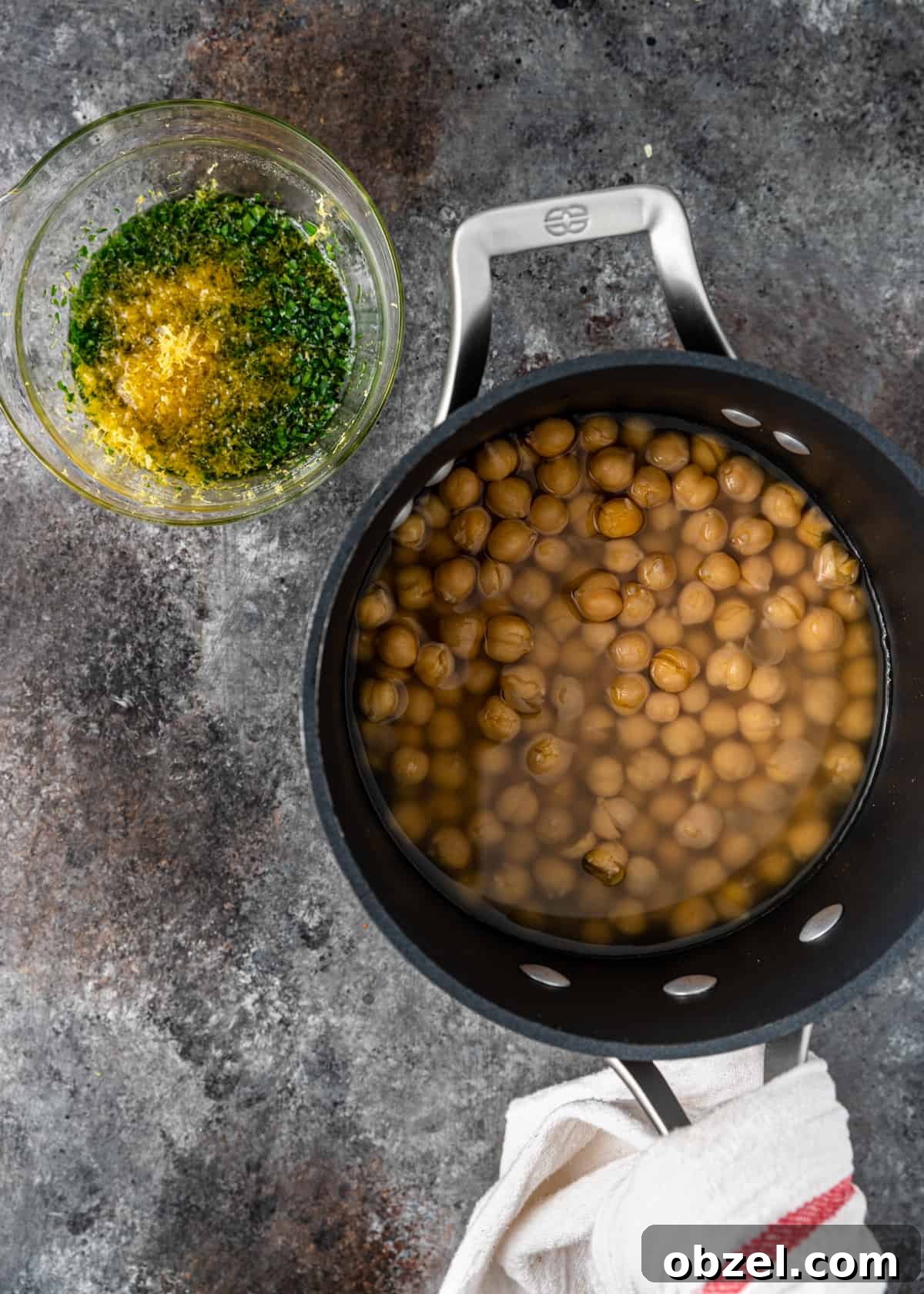 Fatteh with Crispy Pita Hummus and Yogurt 6 overhead process shot: bowl of fresh herbs and lemon peel next to pan of soaking chickpeas