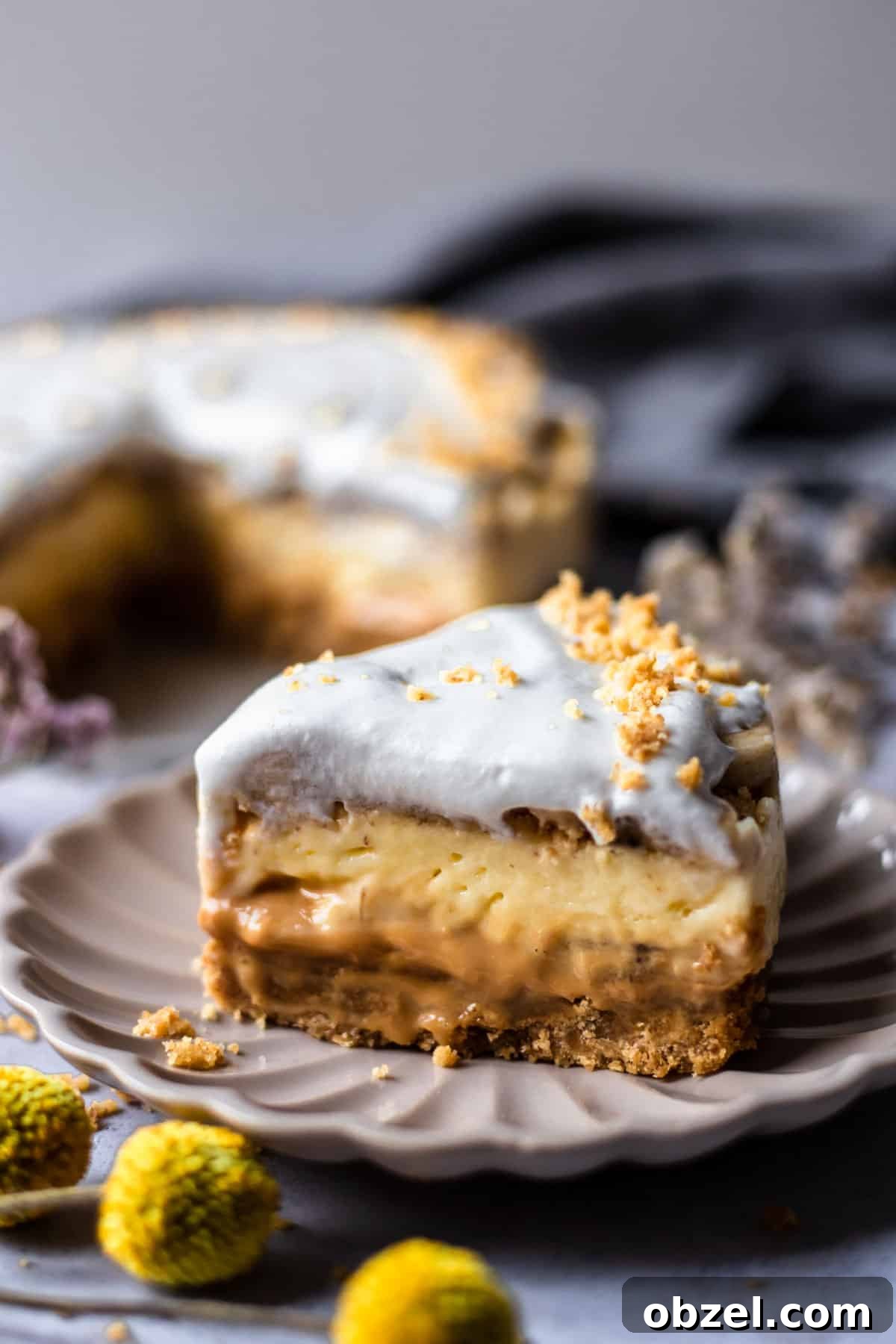 Banoffee Cream Pie with Dulce de Leche and Bananas 2 side view of a piece of banoffee pie on a beige plate showing the layers of crust, dulce de leche, and cream