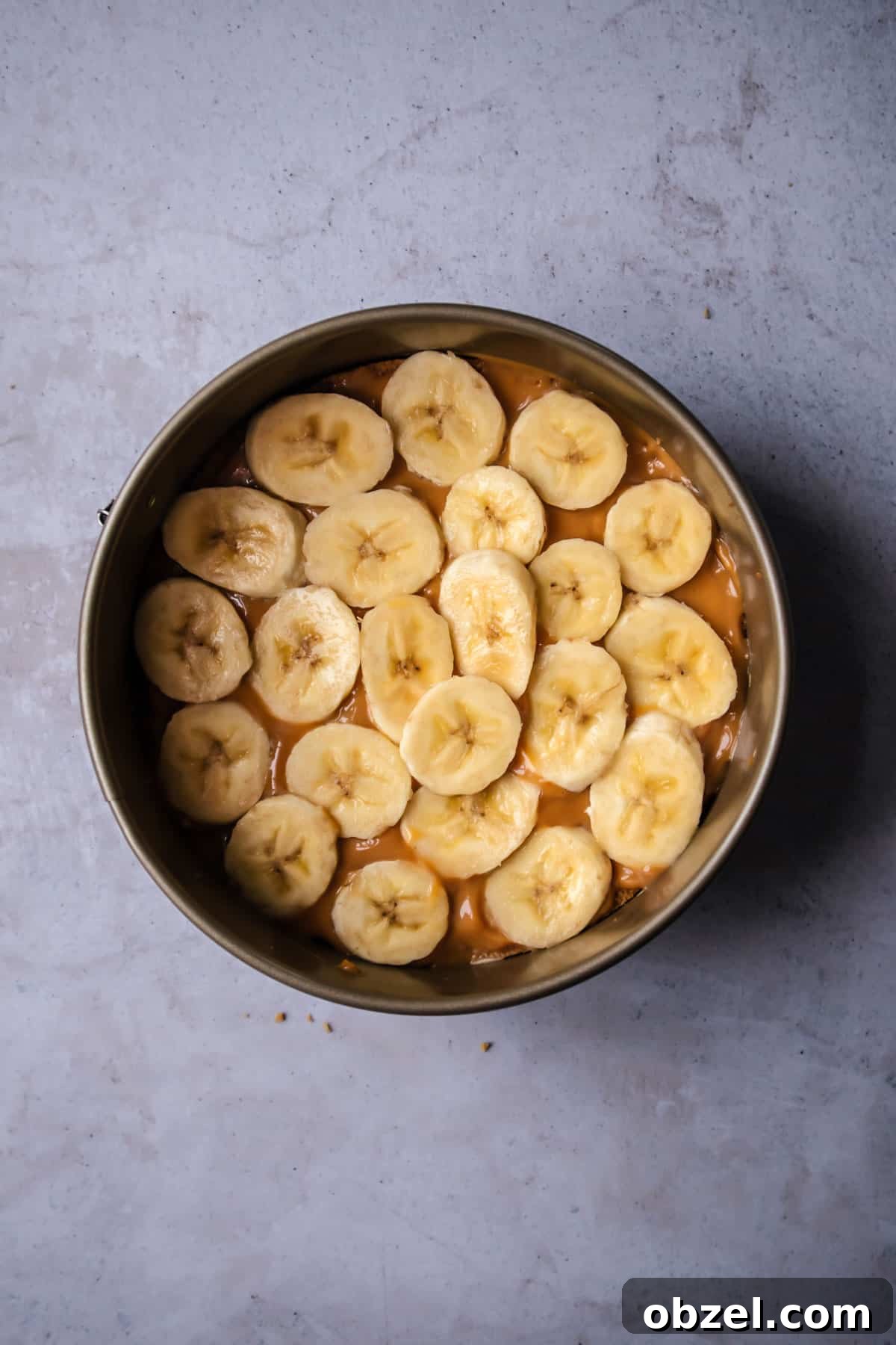 Banoffee Cream Pie with Dulce de Leche and Bananas 5 overhead image of a cake pan with a graham cracker crust topped with a layer of dulce de leche and banana slices