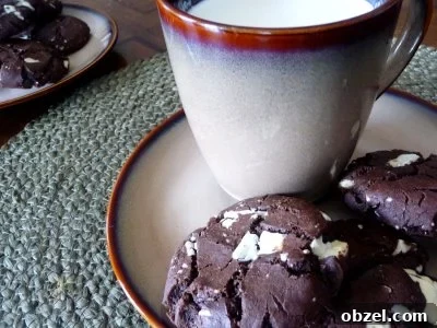 Triple Chocolate Chunk Cookies Recipe 2 Triple chocolate chunk cookies on a small plate with a mug of milk.