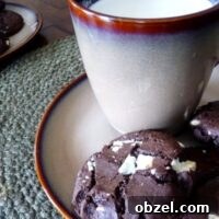 Triple chocolate chunk cookies on a small plate with a mug of milk.