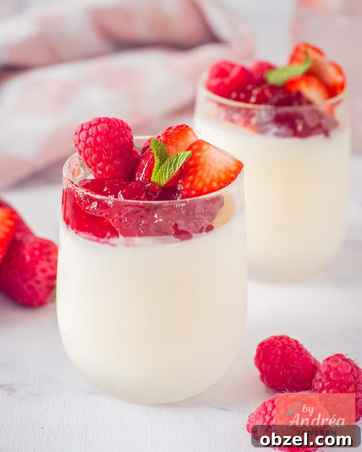 Homemade Berry Frozen Yogurt 2 Two small glasses placed diagonally behind each other, with frozen yogurt at the bottom and a topping of jam and red fruit.