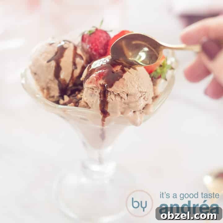 A square photo with a coupe with three scoops of chocolate yogurt ice cream, strawberries and chocolate sauce. A golden spoon takes a bite.