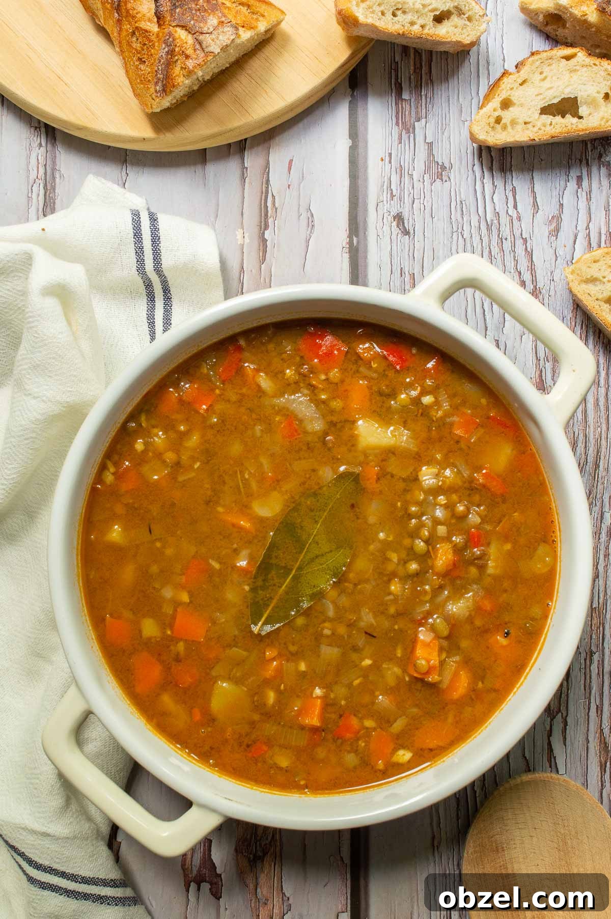 Traditional Spanish Lentil Stew with Chorizo 2 A white casserole dish with lentil stew in it and bread around it.