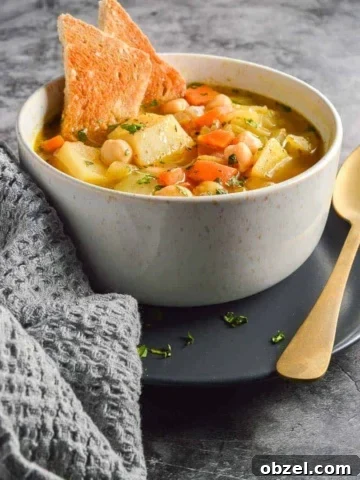 A beige bowl with chunks of potato and carrots in broth and two pieces of toast