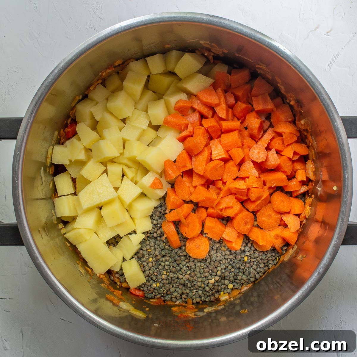 Traditional Spanish Lentil Stew with Chorizo 9 Chopped potatoes, carrots and uncooked lentils in a pot.
