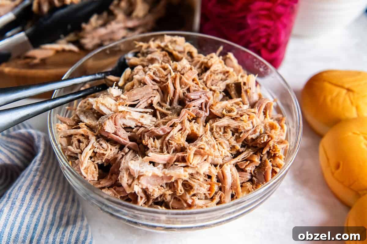 Slow Cooker Pulled Pork Recipe 4 Tongs resting in a bowl of pulled pork.