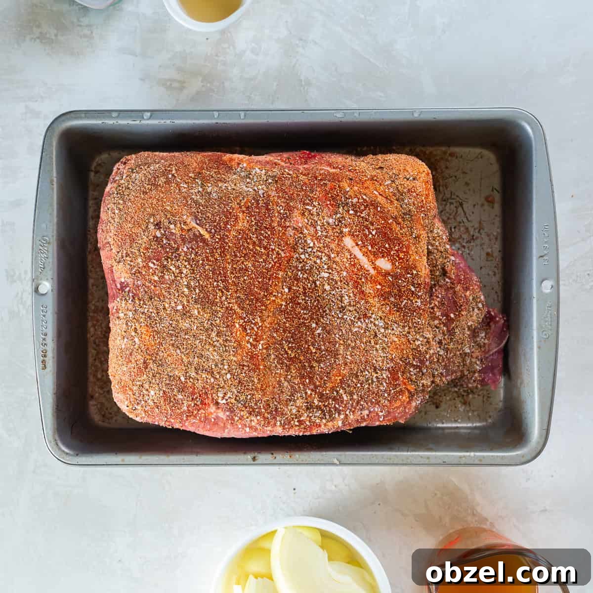 Slow Cooker Pulled Pork Recipe 5 Pork shoulder coated with spice rub in a baking dish before cooking.