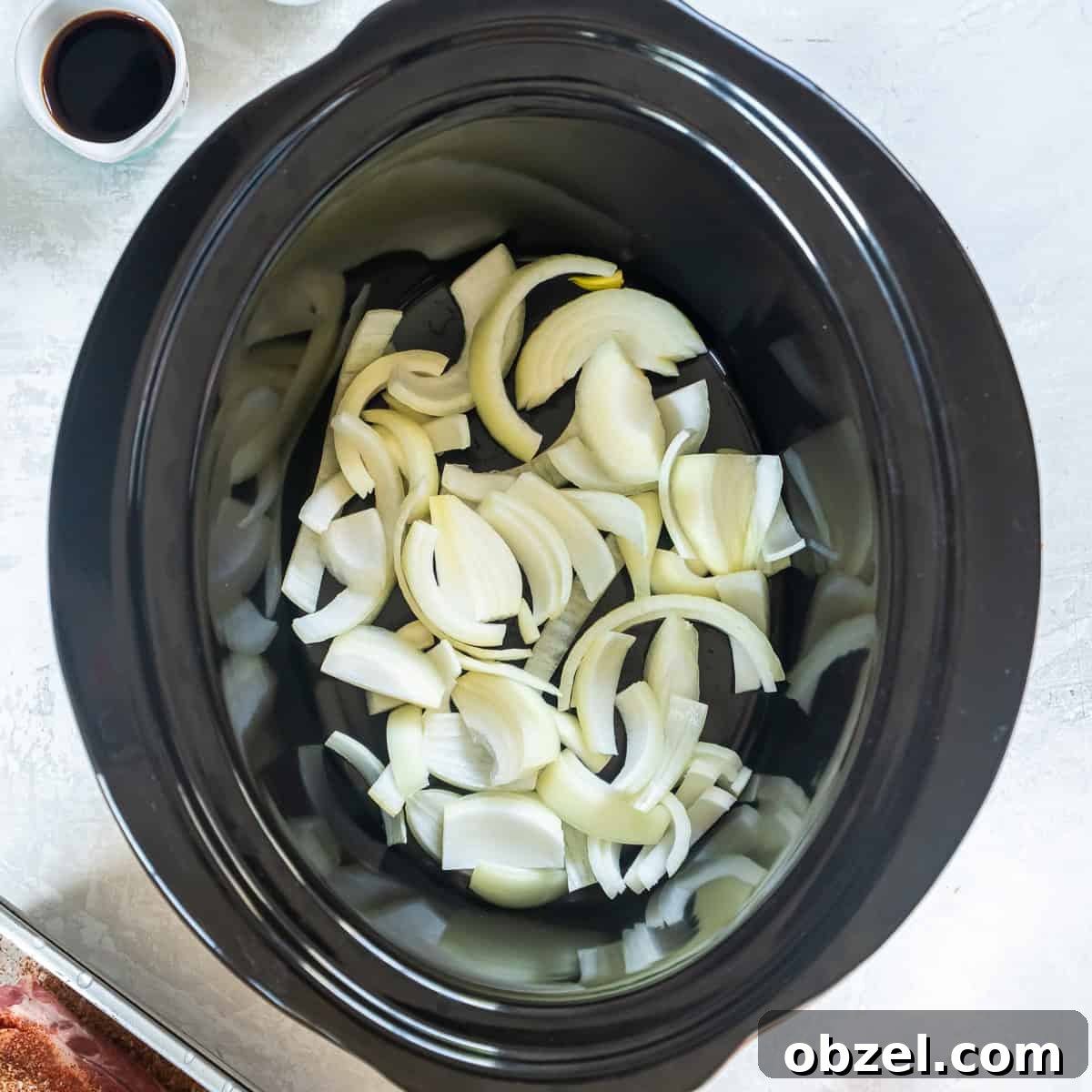Slow Cooker Pulled Pork Recipe 6 Sliced onions placed in the bottom of a slow cooker.