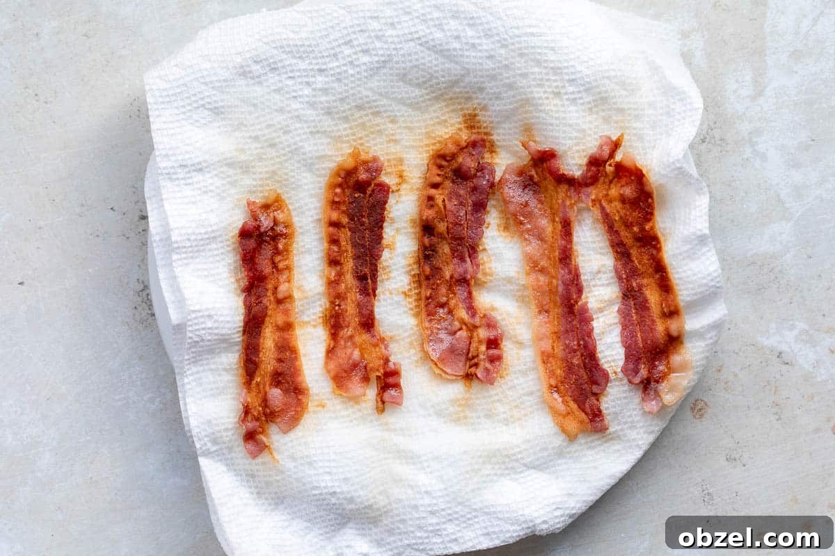 Mini Spinach Egg Bites: Oven-Baked Breakfast Recipe 4 Five crispy bacon strips on a white paper towel absorbing grease.
