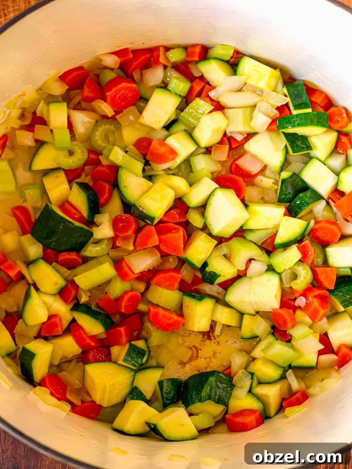 Homemade Bone-In Chicken Soup Recipe with Rich Broth 5 A pot filled with diced onion, carrots, celery and zucchini.