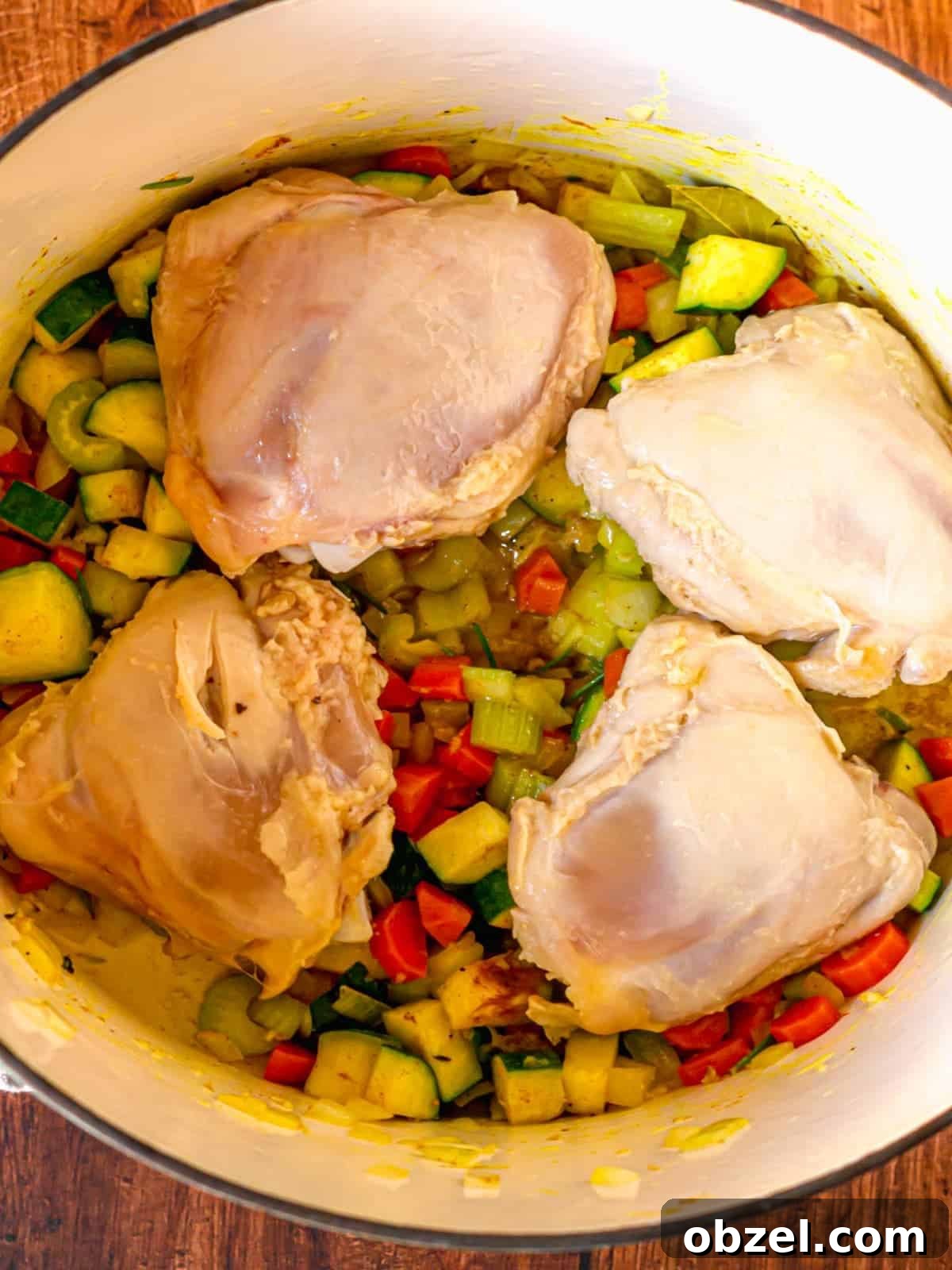 Homemade Bone-In Chicken Soup Recipe with Rich Broth 6 Chicken thighs on a bed of vegetables in a pot.
