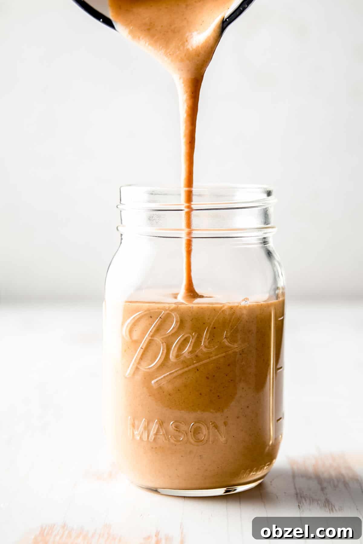 A stream of copycat Starbucks pumpkin spice sauce pouring into a mason jar.
