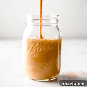 A stream of copycat Starbucks pumpkin spice sauce pouring into a mason jar.