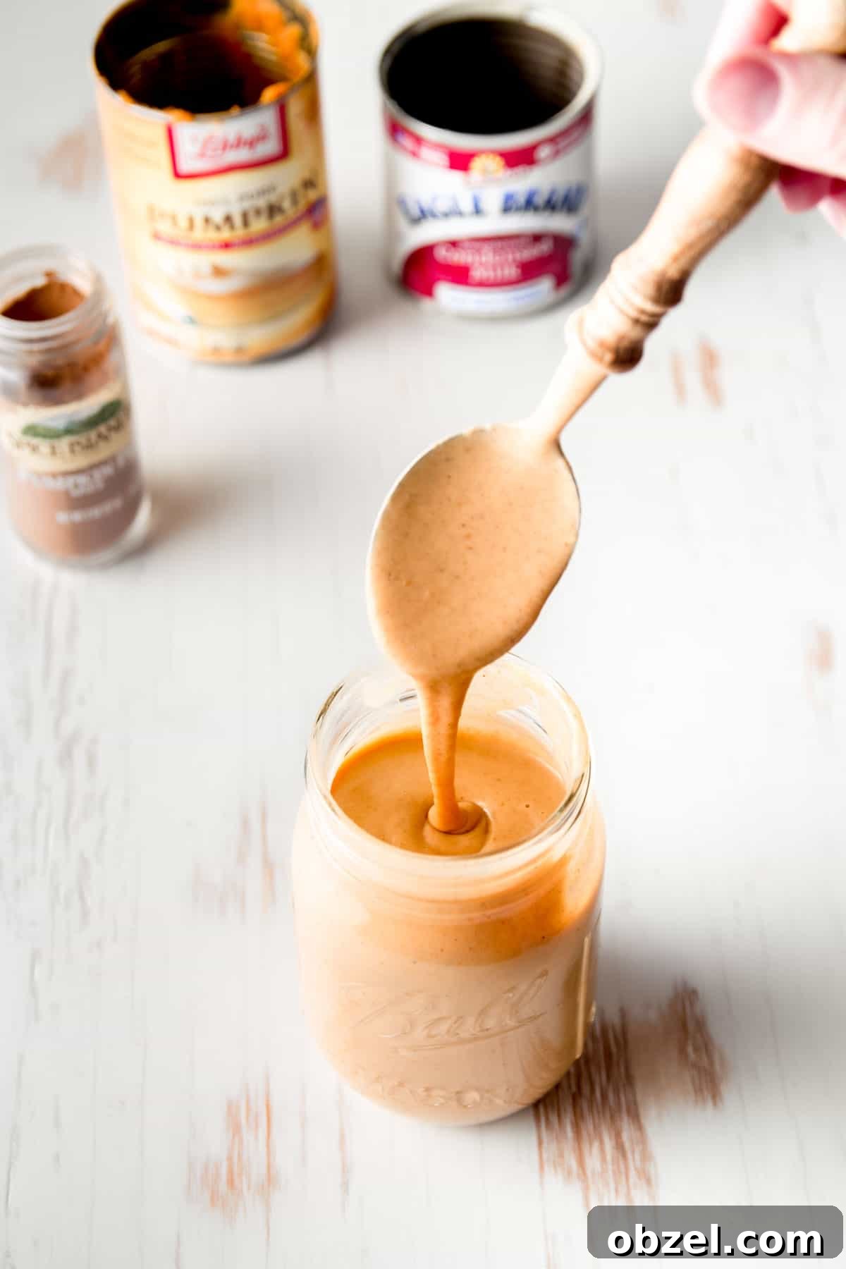 Pumpkin sauce drizzling from a spoon into a mason jar.