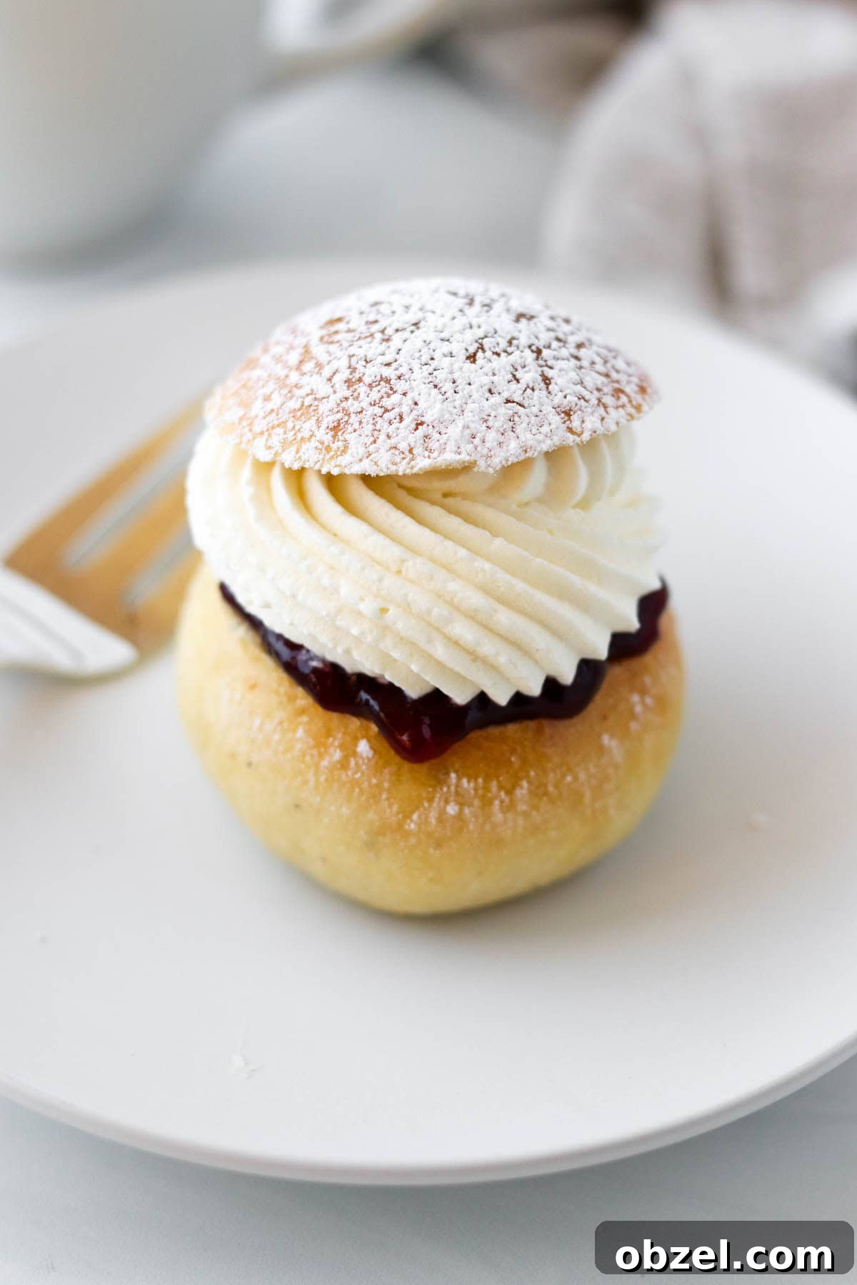Fastelavnsboller: Norwegian Lenten Buns Recipe 2 Fastelavnsboller (Norwegian Lenten Bun) sprinkled with powdered sugar on a white plate.