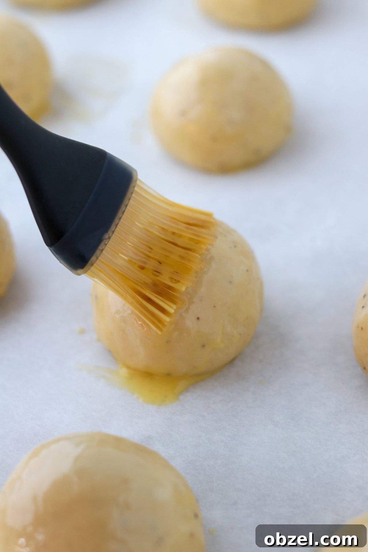 Fastelavnsboller: Norwegian Lenten Buns Recipe 9 Person brushing Fastelavnsboller (Norwegian Lenten Buns) with egg wash.