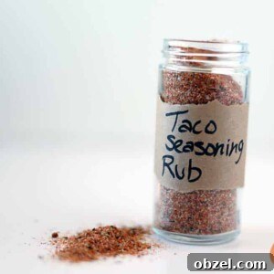 bottle of taco seasoning on white background with some seasoning on table