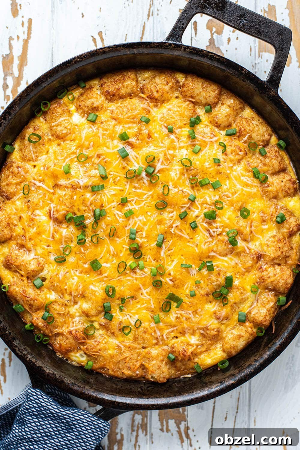 Tater Tot Breakfast Casserole with Eggs and Sausage 2 Golden brown cheesy tater tot breakfast casserole in a cast iron skillet.