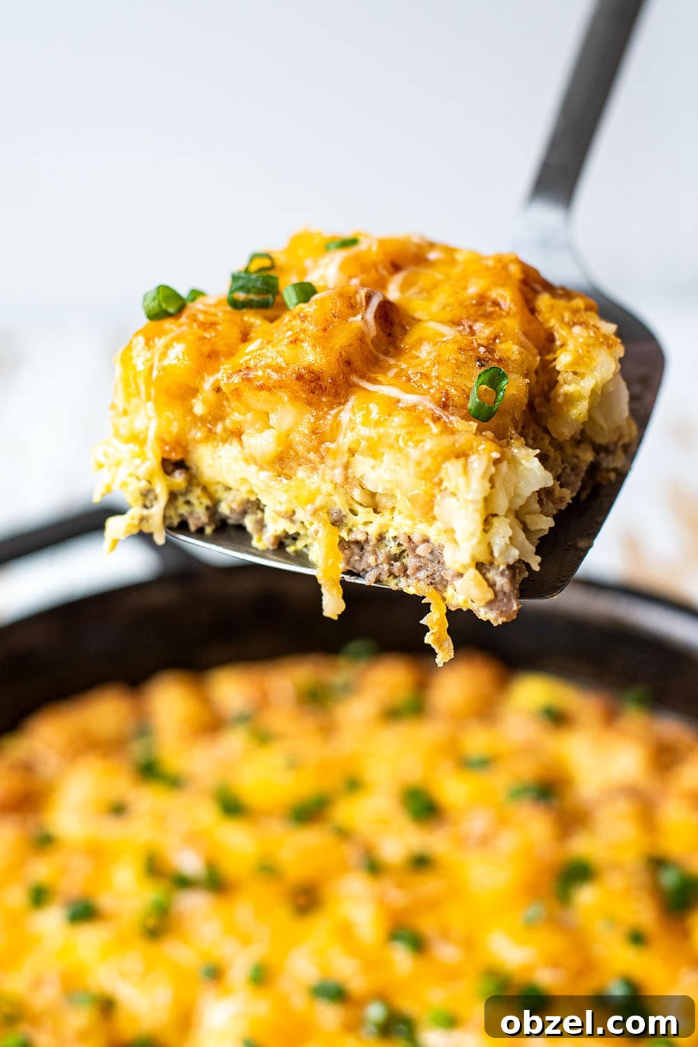Tater Tot Breakfast Casserole with Eggs and Sausage 5 A slice of cheesy golden tater tot breakfast casserole on a spatula.