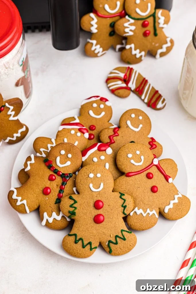 Air Fryer Gingerbread Cookies Recipe 2 Golden gingerbread men on a white plate in front of an air fryer