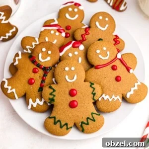 Air Fryer Gingerbread Cookies Recipe 13 Golden gingerbread cookies on a white plate frosted with red, white, and green frosting
