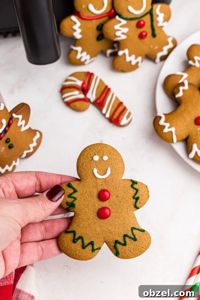 Air Fryer Gingerbread Cookies Recipe 3 Hand holding golden gingerbread man decorated with frosting.