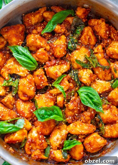 Sticky Basil Chicken in a pot topped with fresh basil.