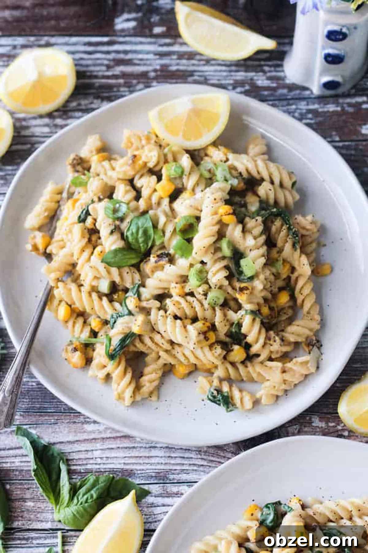 Plate of creamy sweet corn pasta topped with basil leaves.