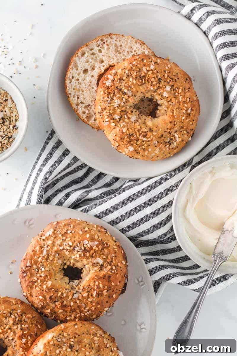 2-Ingredient Gluten-Free Bagels Recipe 7 two ingredient bagels on a table with cream cheese, one cut in half.