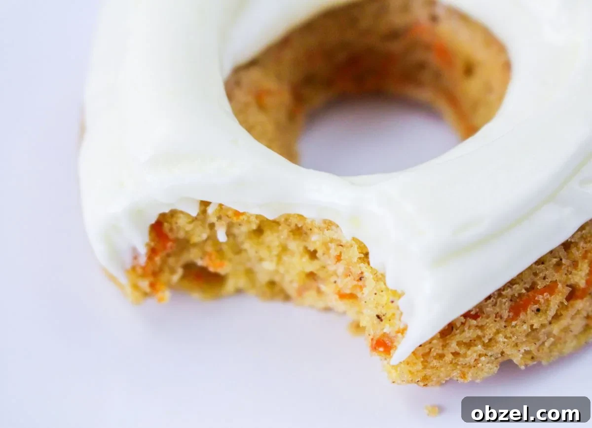 Gluten and Dairy-Free Baked Carrot Cake Donuts 8 Close up of a carrot cake donut with a bite missing.