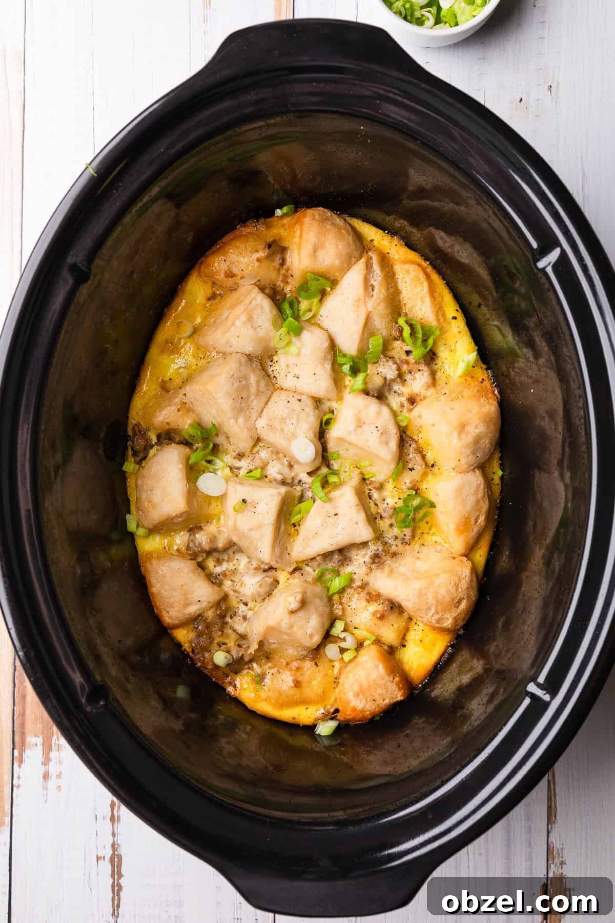 Slow Cooker Biscuits and Sausage Gravy Casserole 2 Crockpot of biscuits and gravy casserole with green onions.