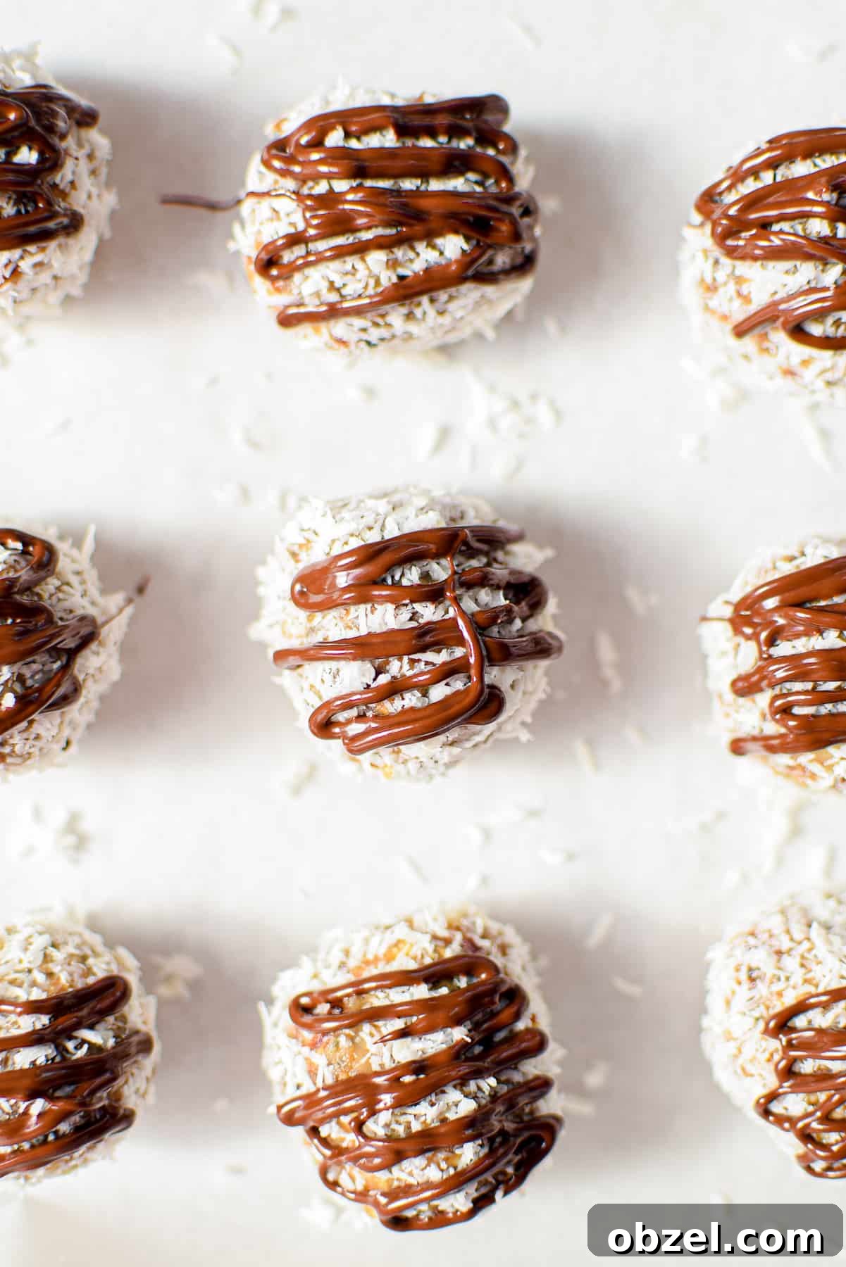 Cannabis Coconut Almond Bliss Balls Recipe 9 A white plate topped with several almond joy cannabis bliss balls garnished with a cannabis fan leaf