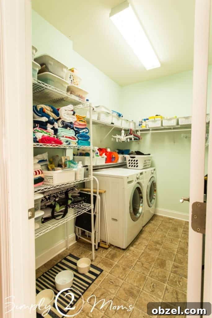 Stunning Before and After Laundry Room Makeover 2 view looking into laundry room from open door washer and dryer on left side of room with wire shelfing above and on wall straight ahead wire storage shelves with towels and bins on left side of room