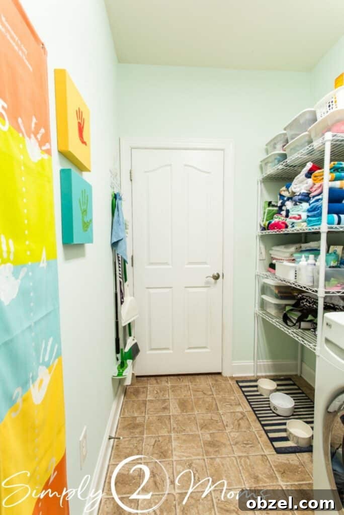 Stunning Before and After Laundry Room Makeover 3 view of laundry room with artwork on leff side with storage shelves on right beyon washer