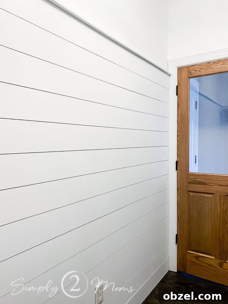 Stunning Before and After Laundry Room Makeover 26 long shiplap wall on right side of photo with custom wood stained door with glass window at end of wall