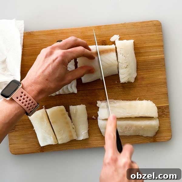 Gluten Free Breaded Fish with Homemade Tartar Sauce 5 Slicing cod fish on a cutting board.