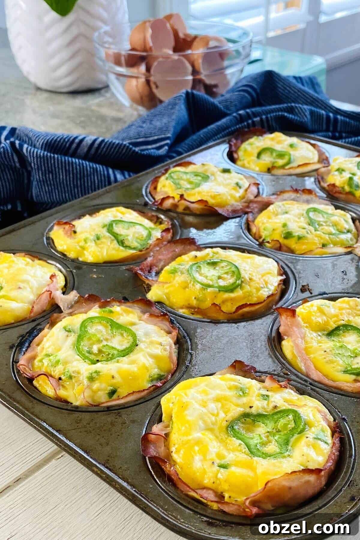 Spicy Jalapeno Popper Egg Cups Recipe 2 jalapeno egg cups in a muffin pan.