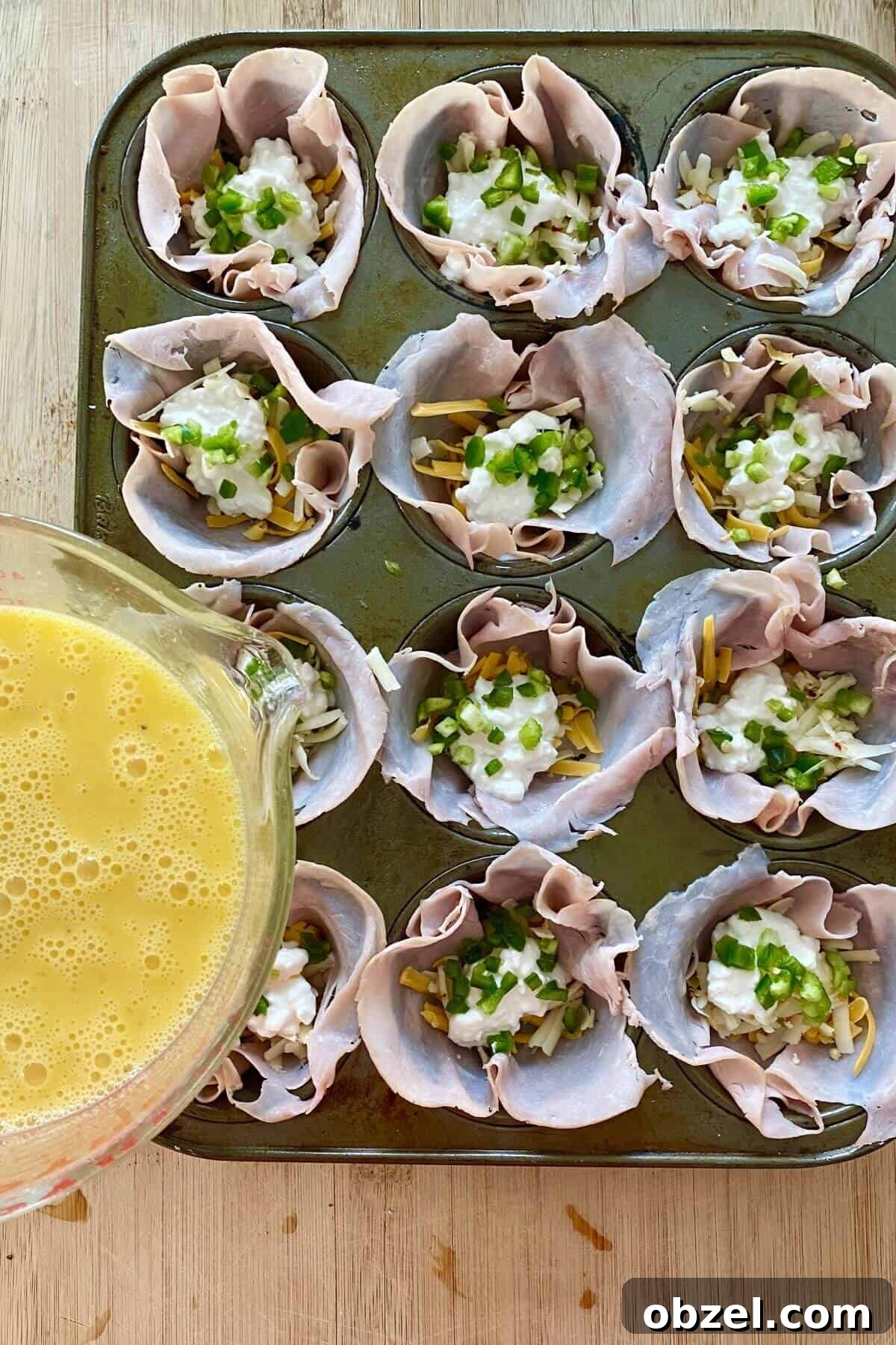 Spicy Jalapeno Popper Egg Cups Recipe 6 filling egg cups with beaten egg.