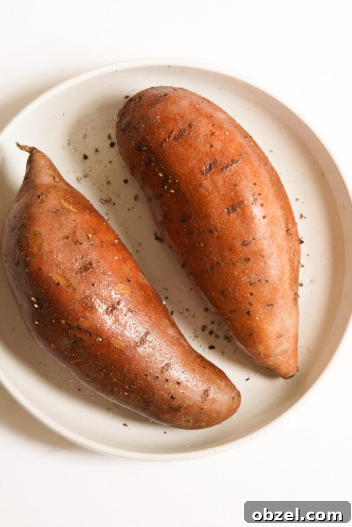 Air Fryer Baked Sweet Potato with Crispy Skin 6 two pierced sweet potatoes covered in olive oil, salt, and black pepper