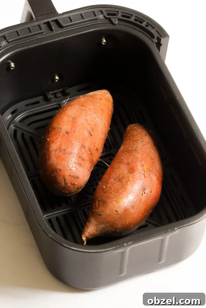 Air Fryer Baked Sweet Potato with Crispy Skin 7 two sweet potatoes in an air fryer basket before cooking