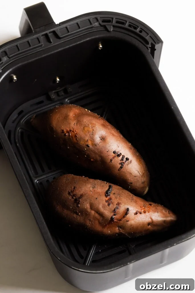 Air Fryer Baked Sweet Potato with Crispy Skin 8 two sweet potatoes in an air fryer basket after cooking