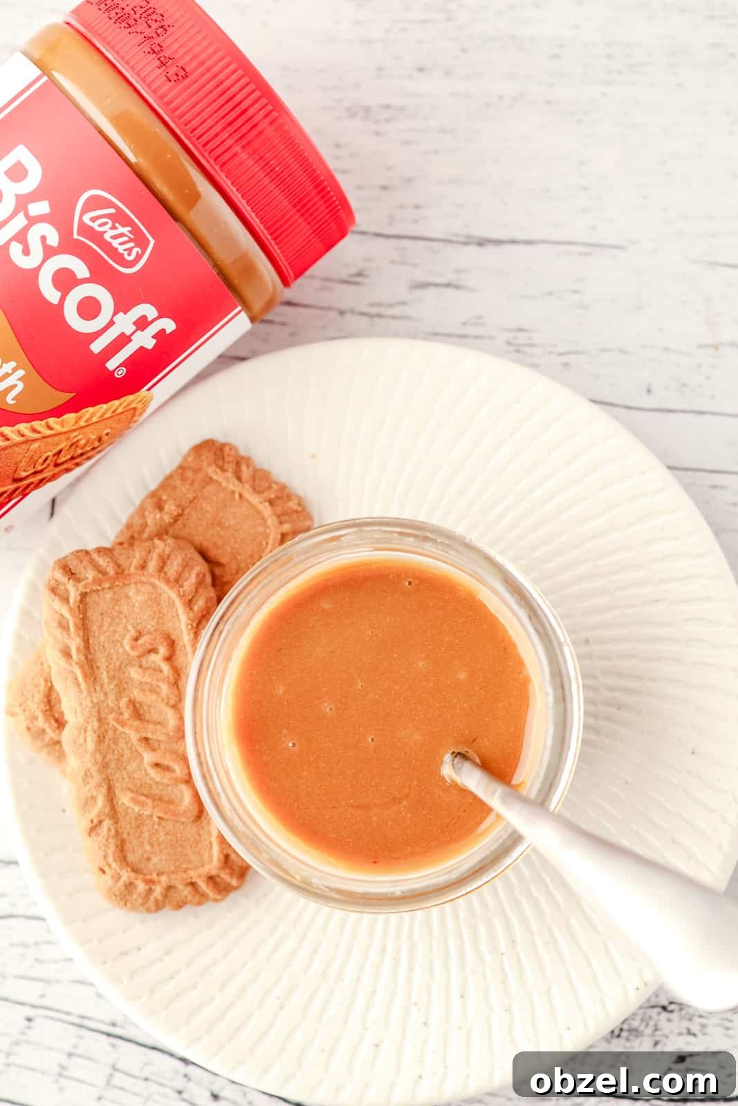 Biscoff Cookie Butter Sauce Recipe 6 Top down shot of Biscoff sauce in a mason jar with a spoon in it, and Biscoff cookies and a jar of Biscoff spread on the side.