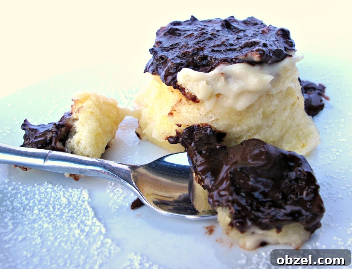 Spoonful of chocolate covered Boston Cream Pie Mug Cake with the cake in the background.