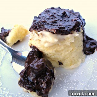 Boston Cream Pie Mug Cake on a plate behind a spoon full of cake covered in melted chocolate.