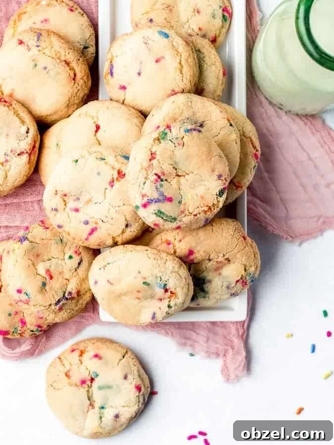 Fluffy Sprinkle Cookies on plate with pink cloth underneath and milk off to the side, shot from overhead